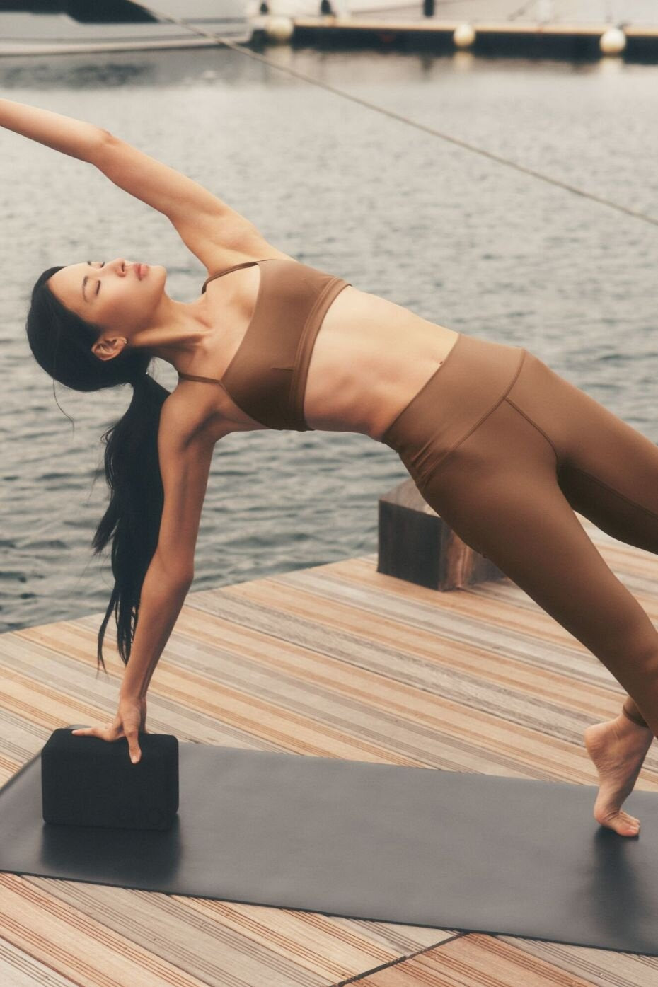 Femme en planche latérale sur un tapis de yoga, sur un ponton en bois